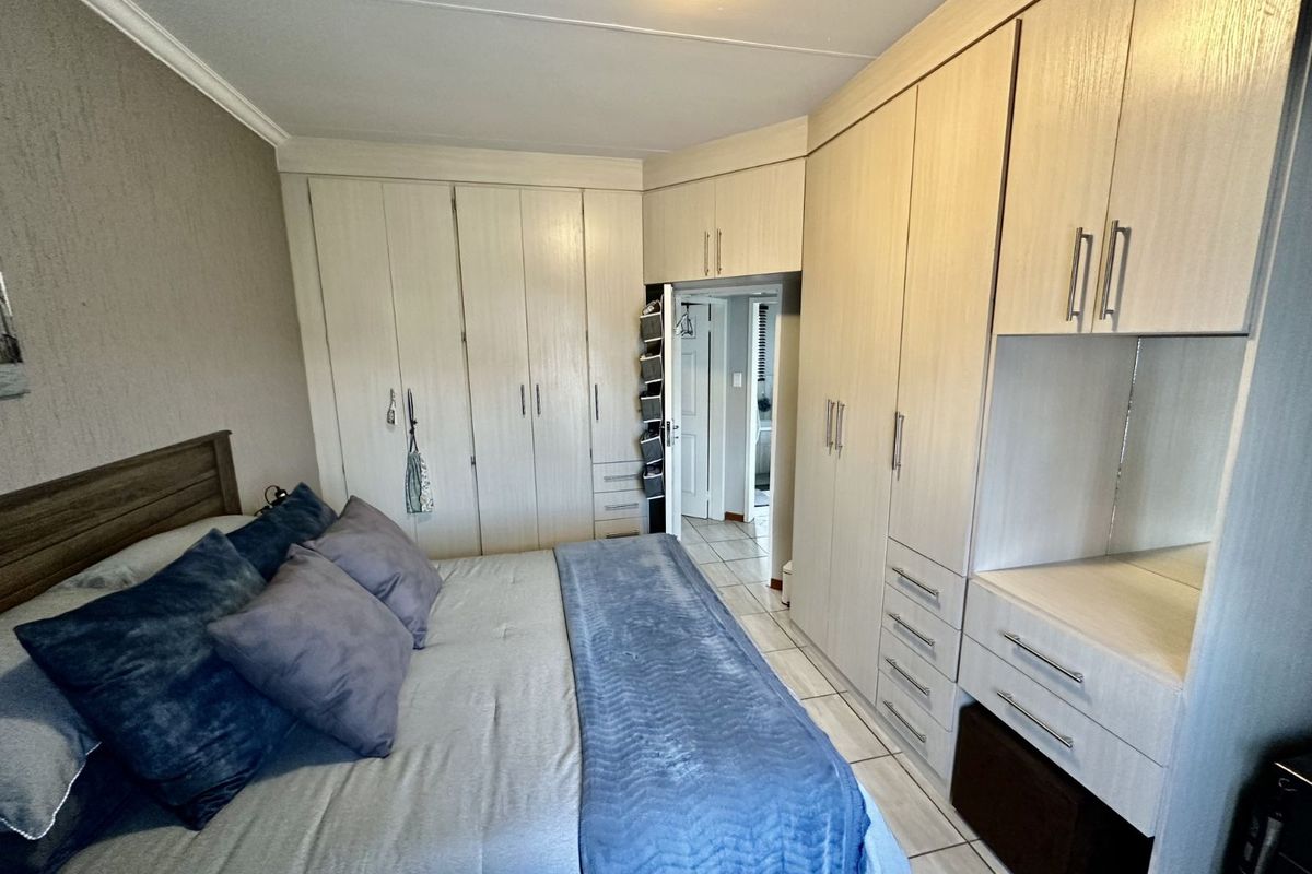 A bedroom featuring extensive built-in cabinetry with integrated storage and vanity space, finished in a light wood-grain laminate.