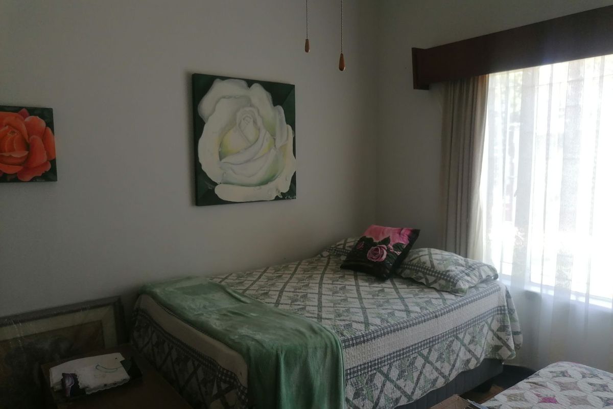 A bedroom featuring a window with a wooden pelmet and neutral wall finishes.