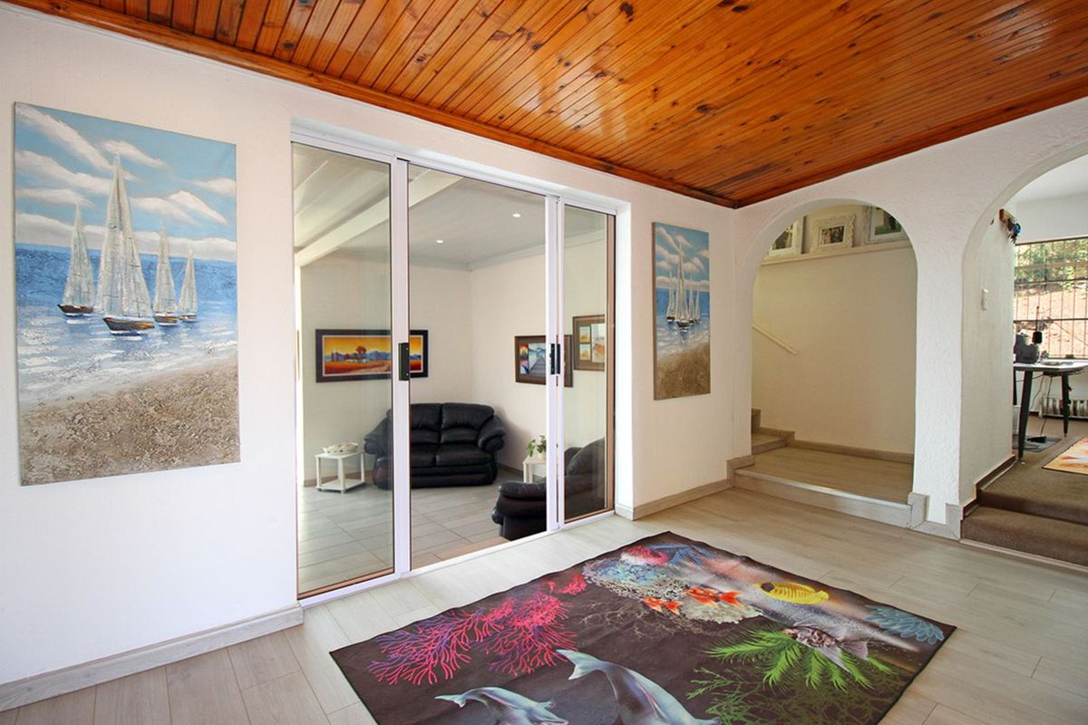 Spacious living area featuring a timber-clad ceiling, arched entryway, and large sliding glass doors leading to an adjacent room.