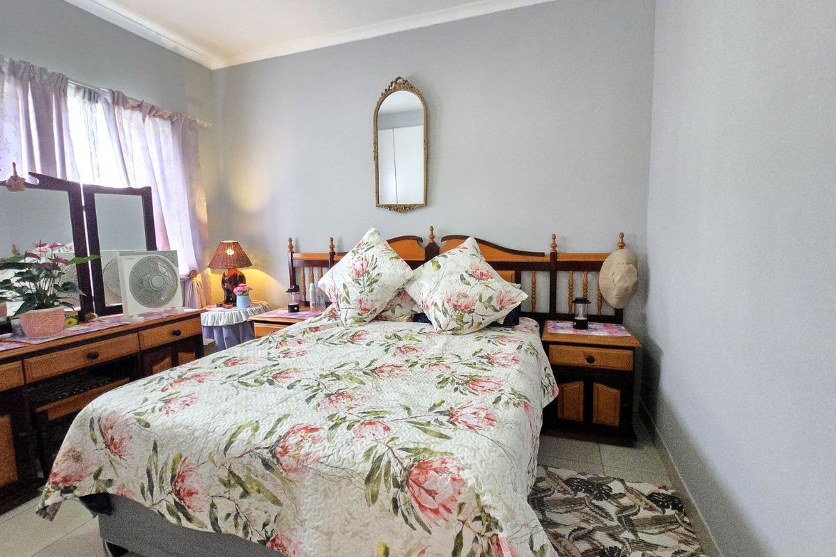 A well-maintained bedroom featuring neutral wall tones, tiled flooring, and classic crown molding, providing a comfortable and functional living space.