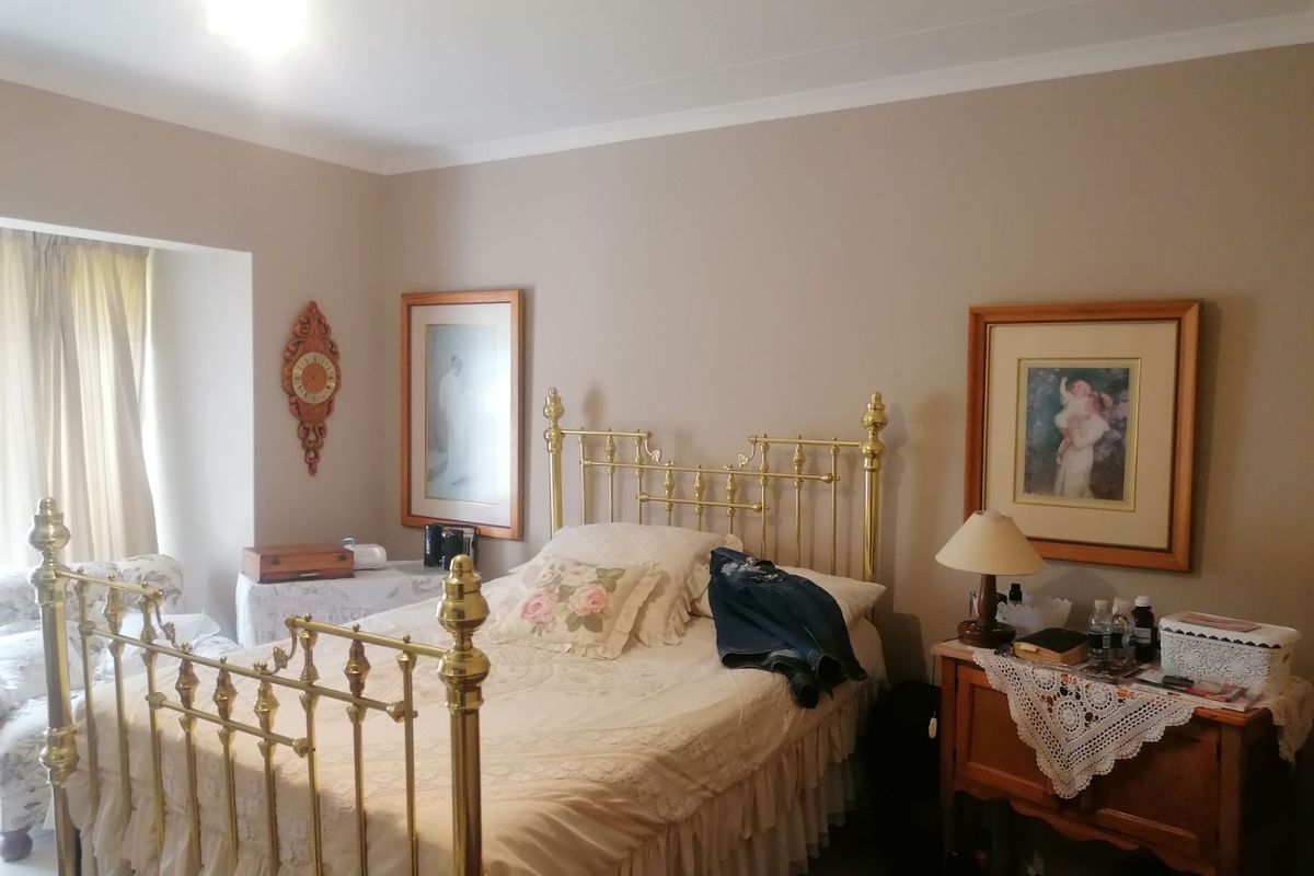 A bedroom featuring neutral wall tones, coved ceiling cornices, and a window with curtain tracks.