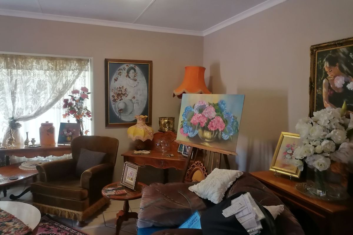 A living room area featuring tiled flooring and a window with curtaining, providing a functional space for relaxation.