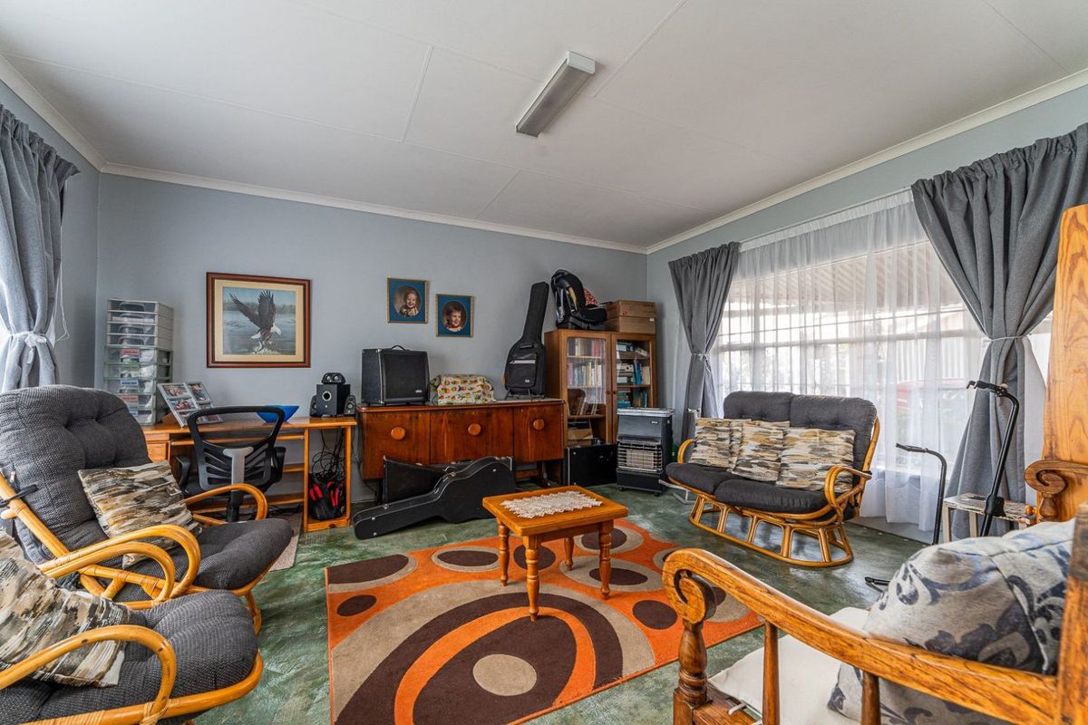 A living room featuring large windows, neutral wall paint, and patterned flooring, offering a functional space ready for modernization and personal updates.