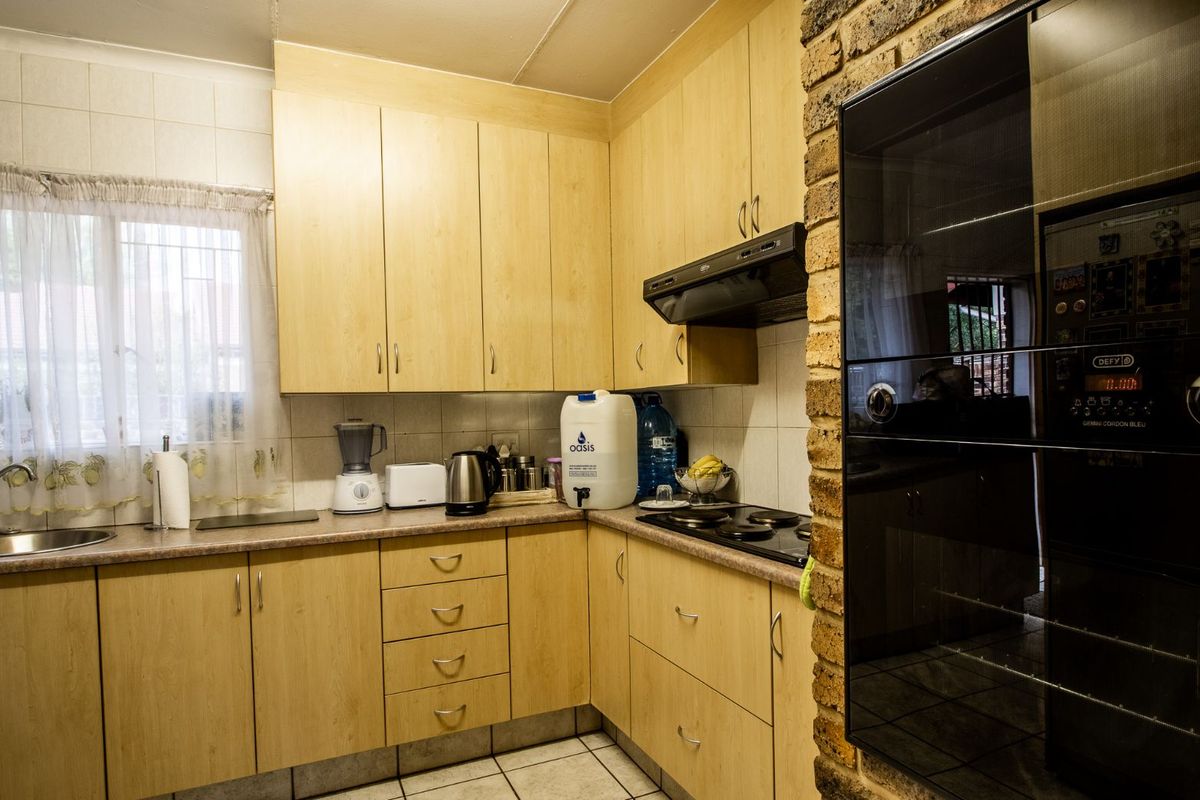 A functional kitchen featuring light wood-finish cabinetry, laminate countertops, a built-in oven, and a hob with an extractor fan.