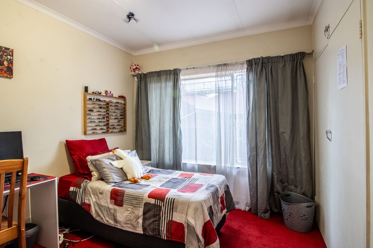 A standard bedroom featuring built-in cupboards, carpeted flooring, and a window with curtain tracks.