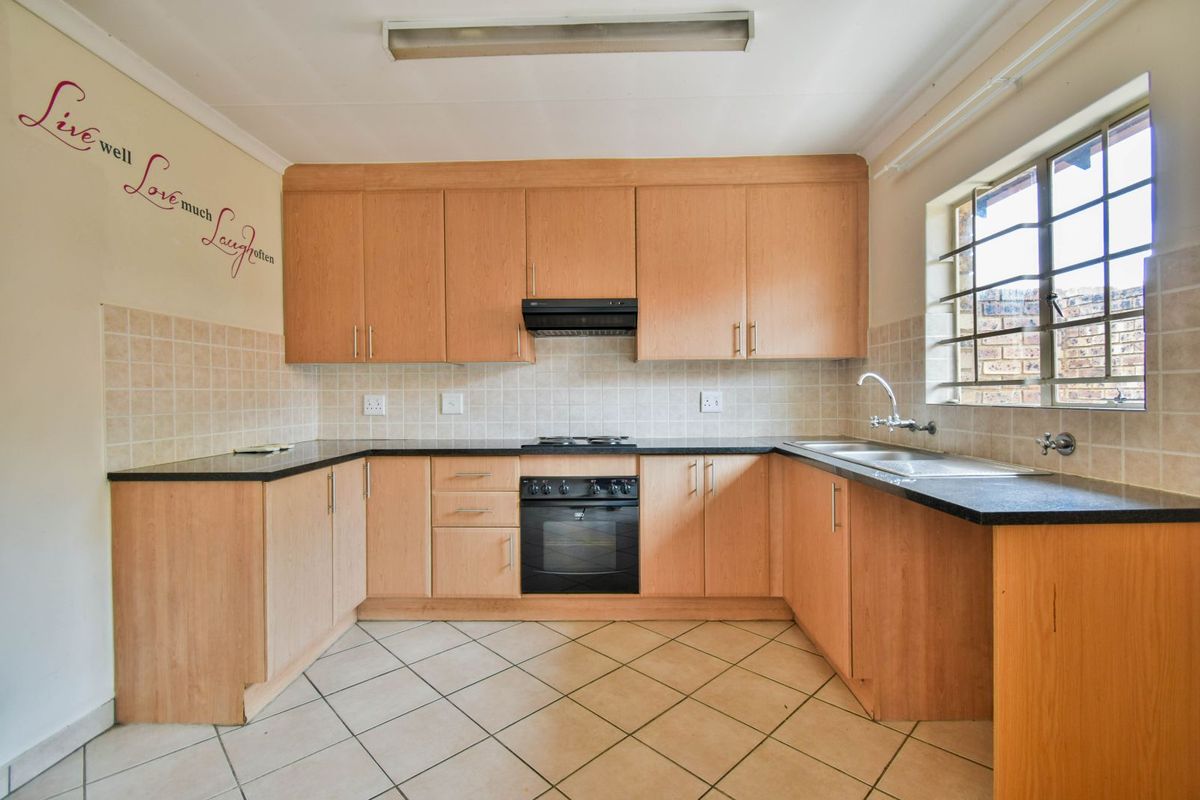 Functional U-shaped kitchen featuring light wood cabinetry, dark countertops, built-in oven, hob, extractor fan, and a double basin sink with tiled backsplash.