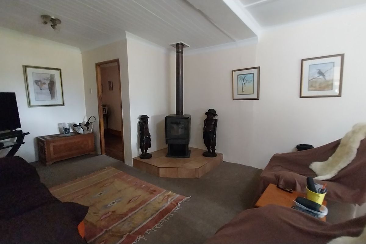 A cozy living room featuring a central wood-burning fireplace with a tiled hearth and tongue-and-groove ceiling detail.