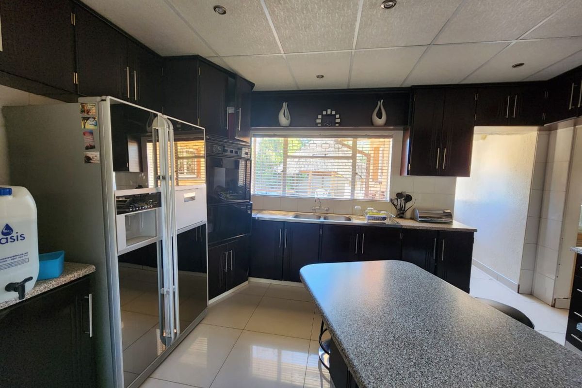A functional kitchen featuring dark cabinetry, granite-style countertops, a central island, and a double sink with a window view.