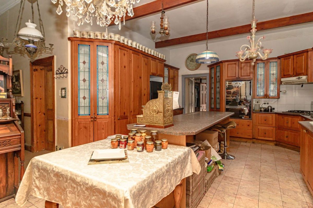 Spacious kitchen featuring extensive wooden cabinetry, a central island with breakfast bar, tiled flooring, and exposed ceiling beams.