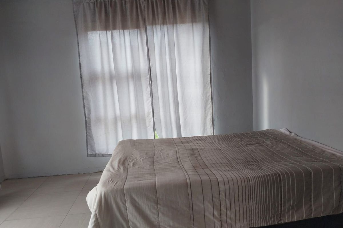A simple bedroom featuring tiled flooring and a wooden ceiling, providing a functional and neutral space.