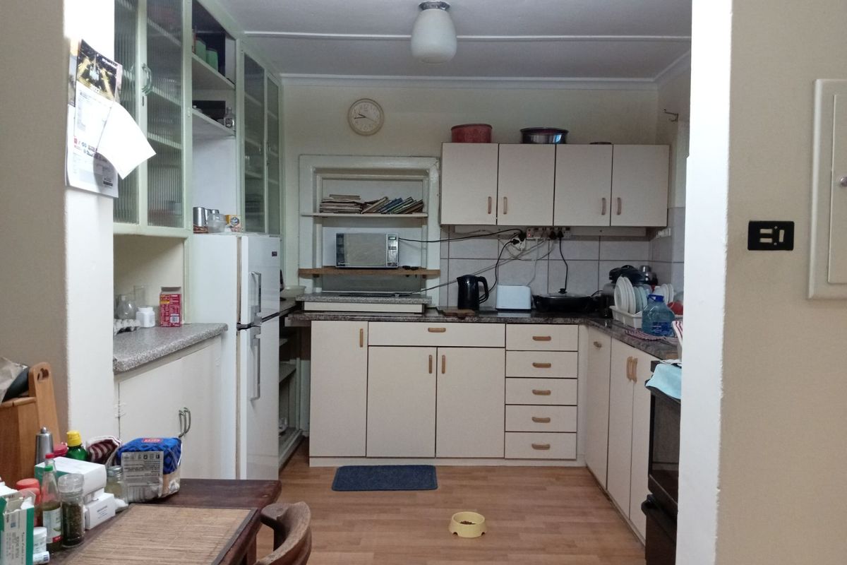 A dated kitchen featuring laminate cabinetry, stone-look countertops, and wood-effect flooring, offering a functional layout with ample storage space.