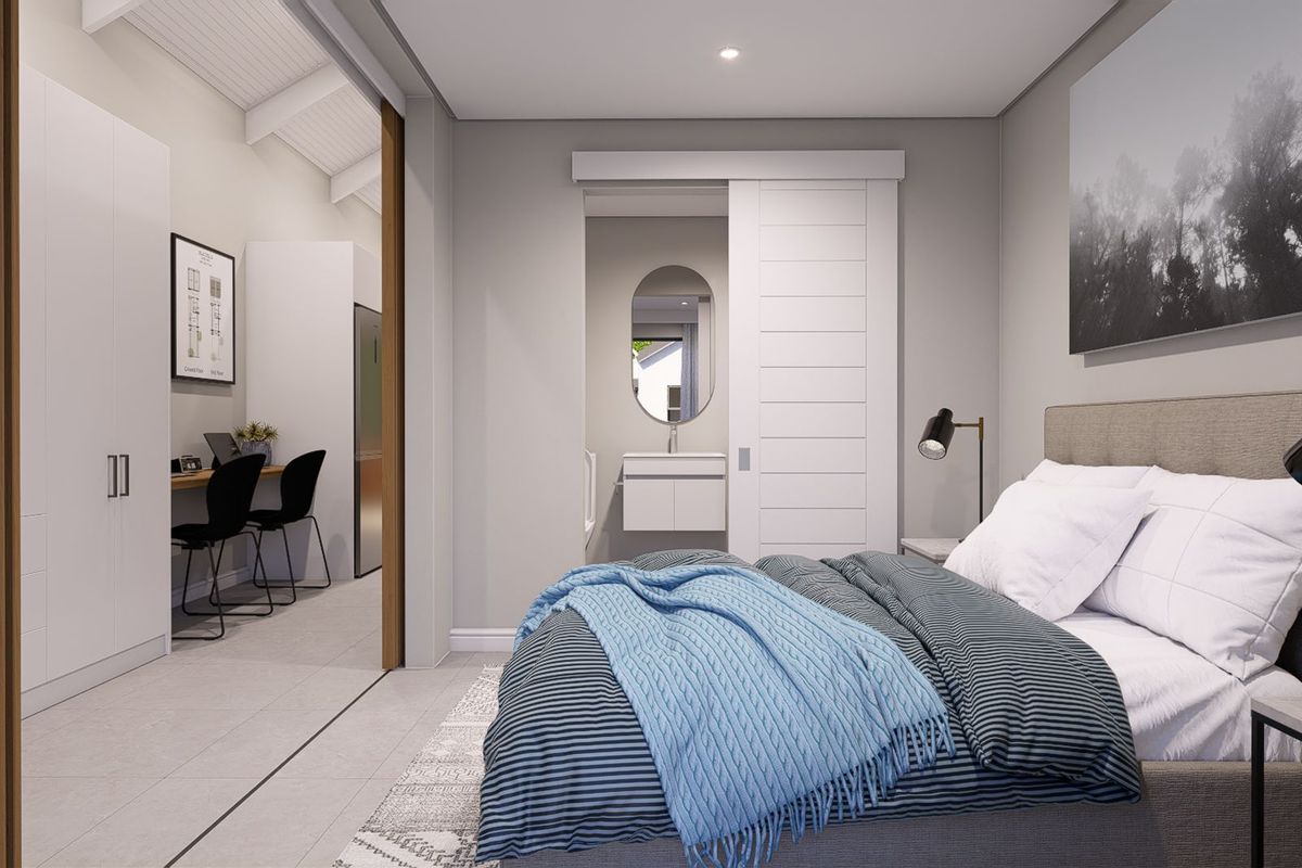 Modern bedroom featuring a sliding barn door leading to an en-suite bathroom, with an adjacent study nook and built-in cabinetry.