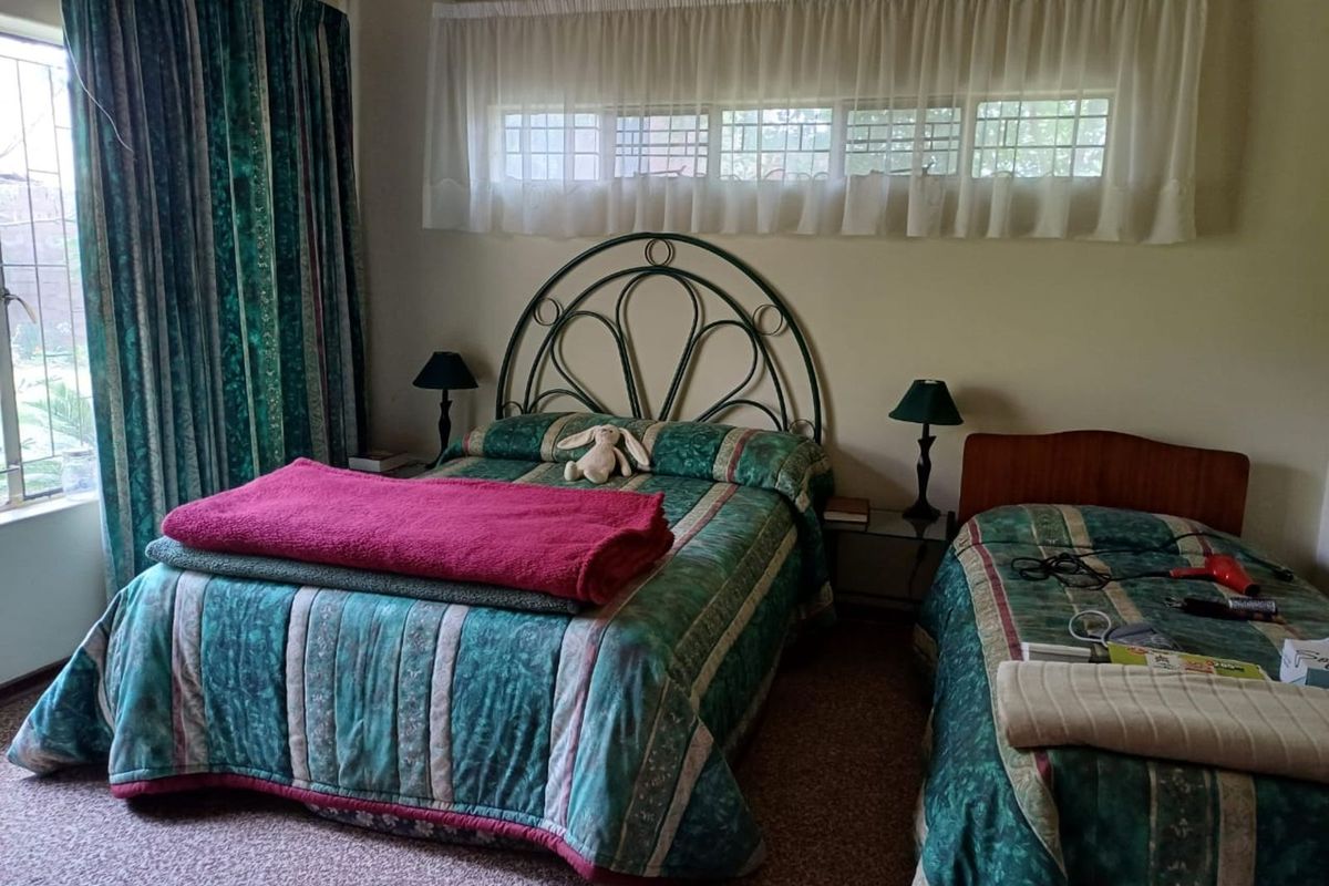 A bedroom featuring carpeted flooring, a large window with curtains, and a built-in curtain pelmet.