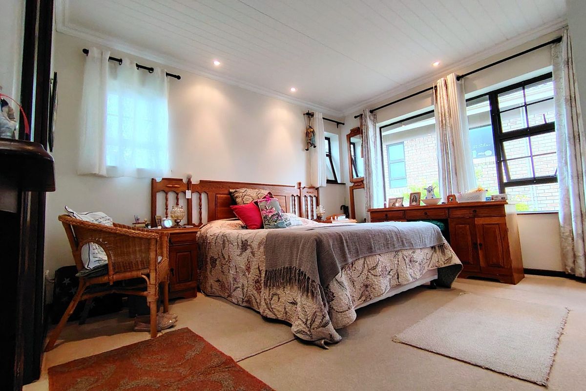 A spacious bedroom featuring neutral carpeting, recessed ceiling lighting, and large windows that provide ample natural light.