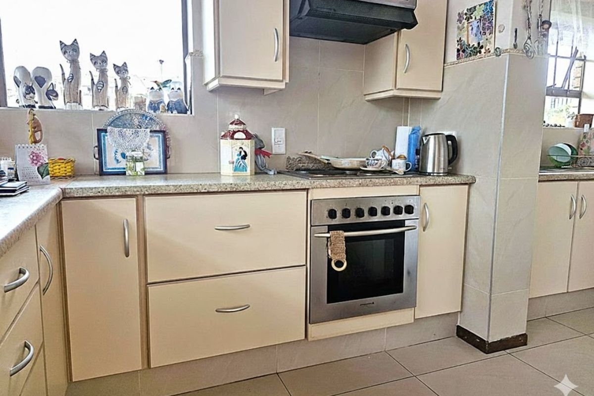 A functional kitchen featuring tiled flooring, neutral cabinetry, granite-style countertops, and a built-in oven with an overhead extractor fan.