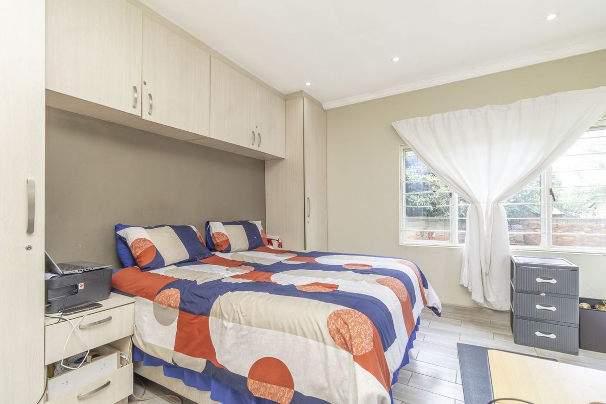 A bedroom featuring built-in cupboards, tiled flooring, and recessed ceiling lighting.