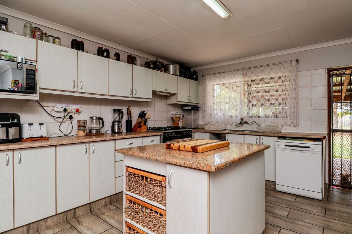 A functional kitchen featuring laminate countertops, built-in cabinetry, a central island, and direct access to an outdoor patio area.