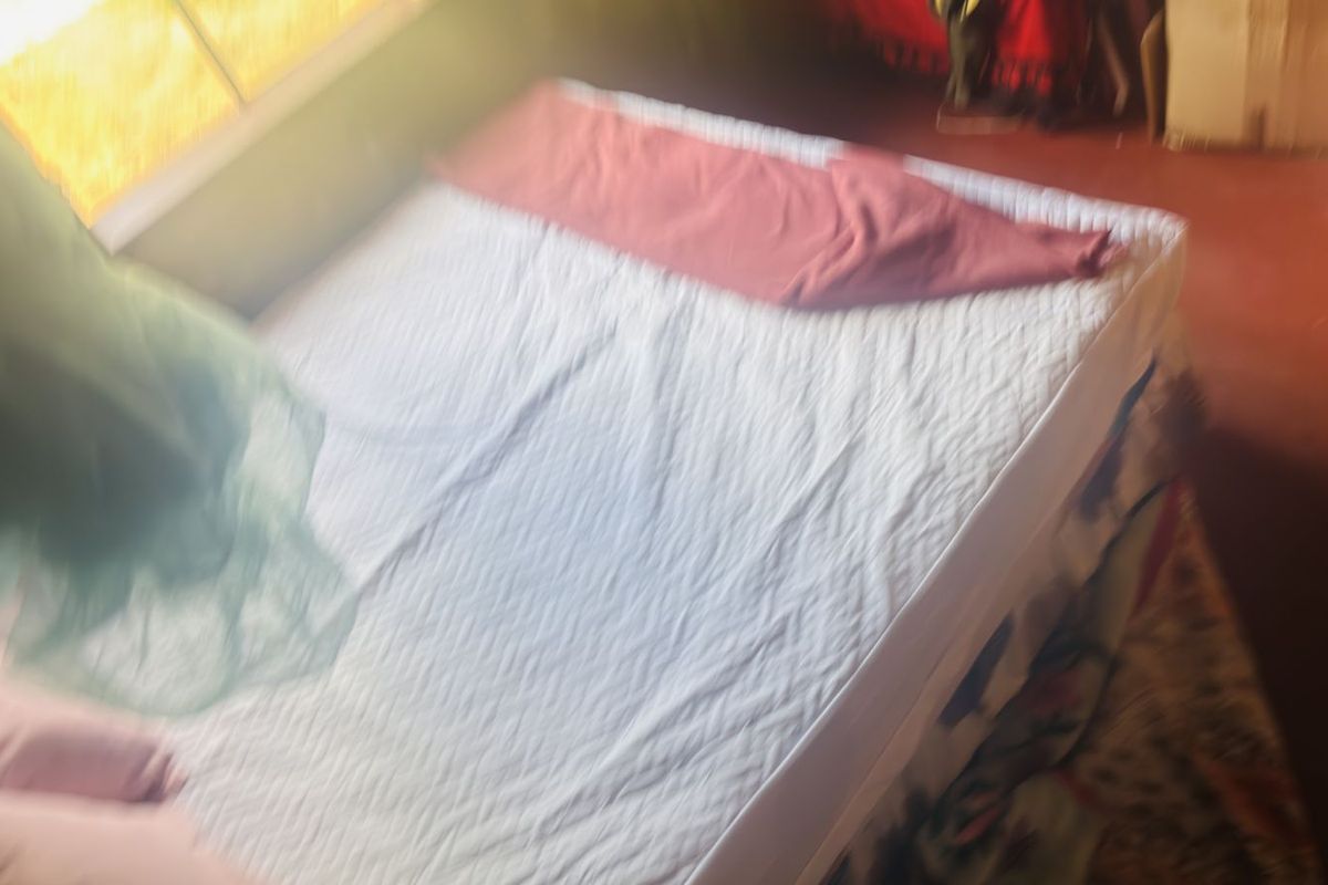 A bedroom space featuring a bed, captured in a low-quality, blurry photograph.