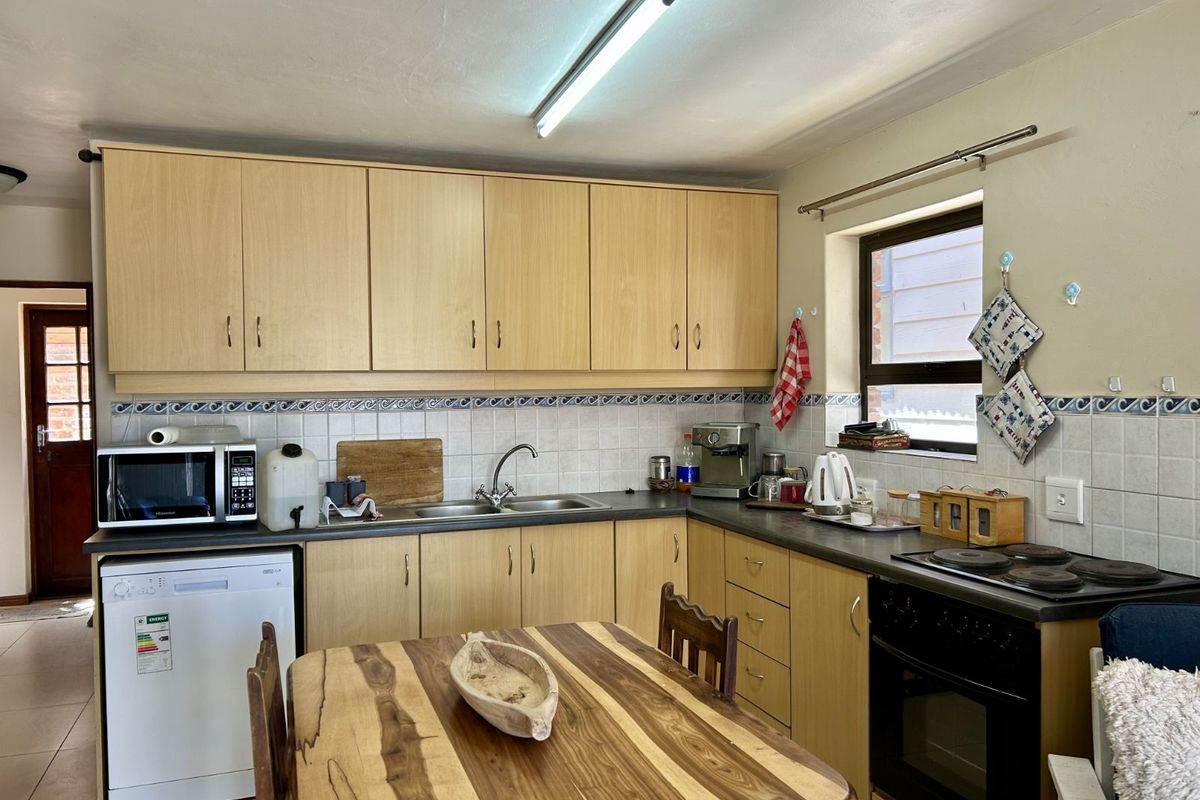 A functional kitchen featuring light wood-tone cabinetry, a tiled backsplash, integrated oven and hob, and a double-basin sink.