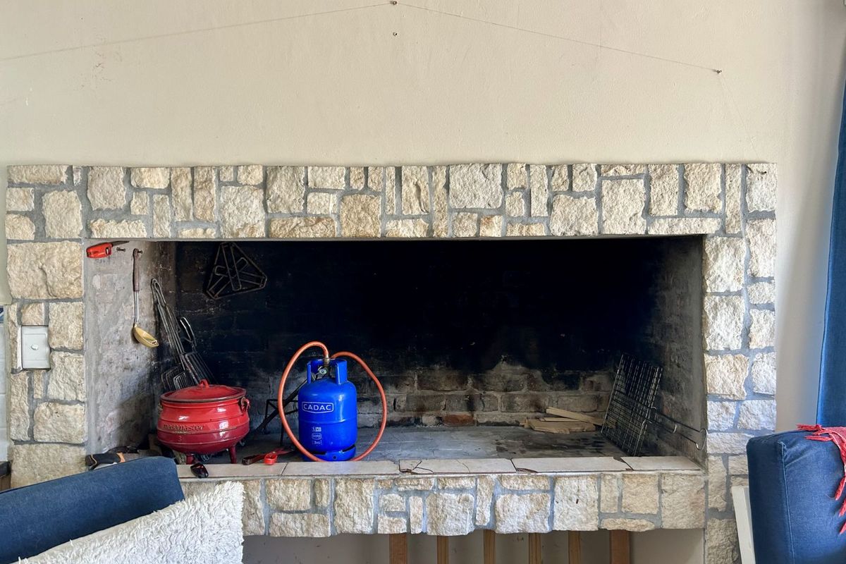 A built-in indoor braai or fireplace featuring a rustic stone facade and tiled hearth, providing a focal point for the living area.