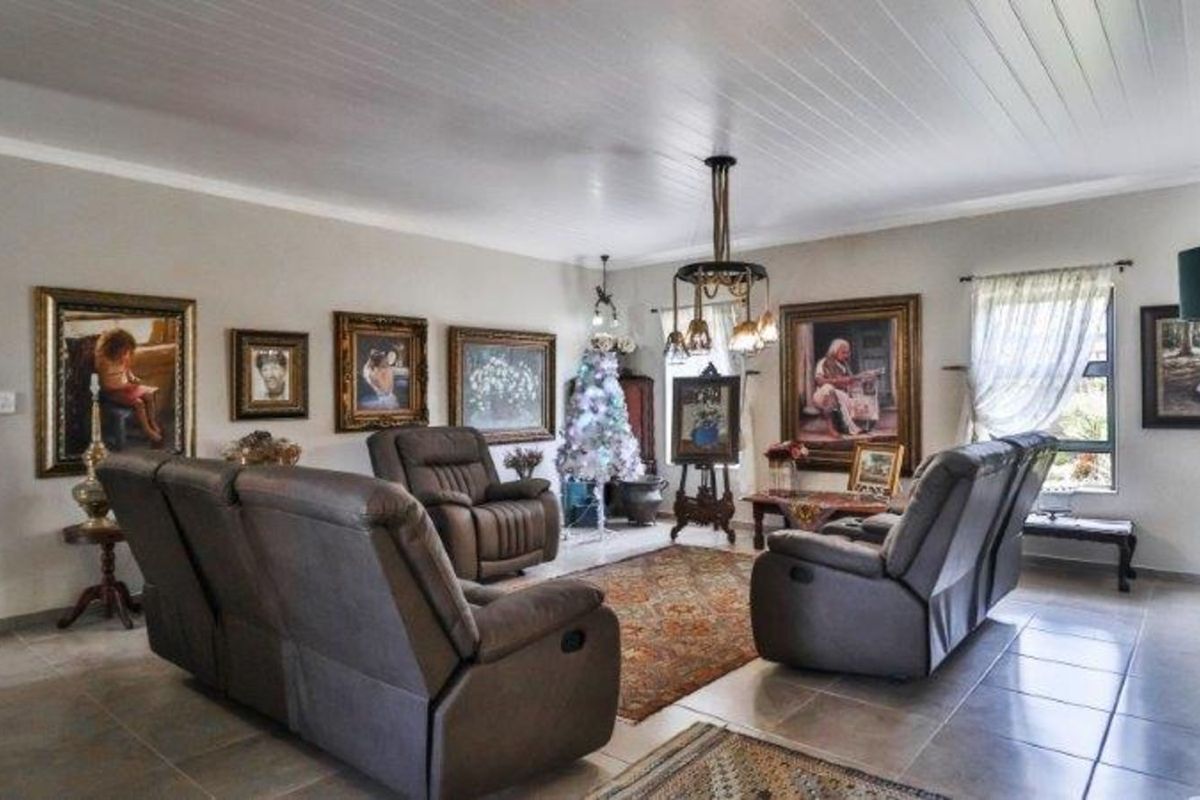 A spacious living room featuring tiled flooring, a white tongue-and-groove ceiling, and a decorative chandelier.