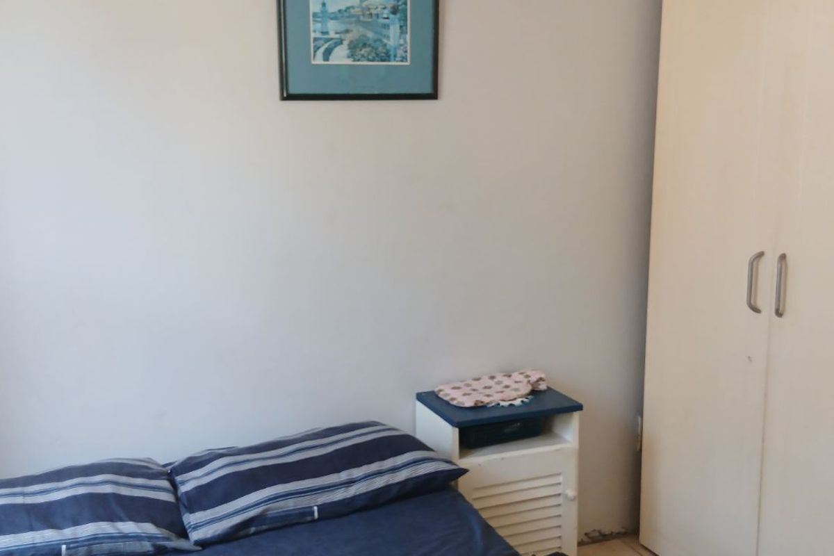 A bedroom featuring a built-in wardrobe with white doors, providing functional storage space.