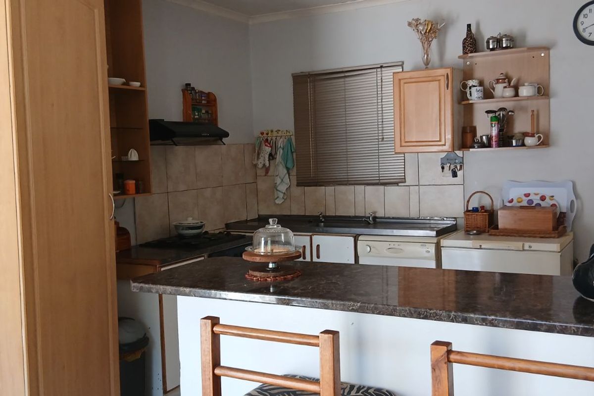 A functional kitchen featuring a breakfast bar, tiled backsplash, built-in cabinetry, and a window with blinds.