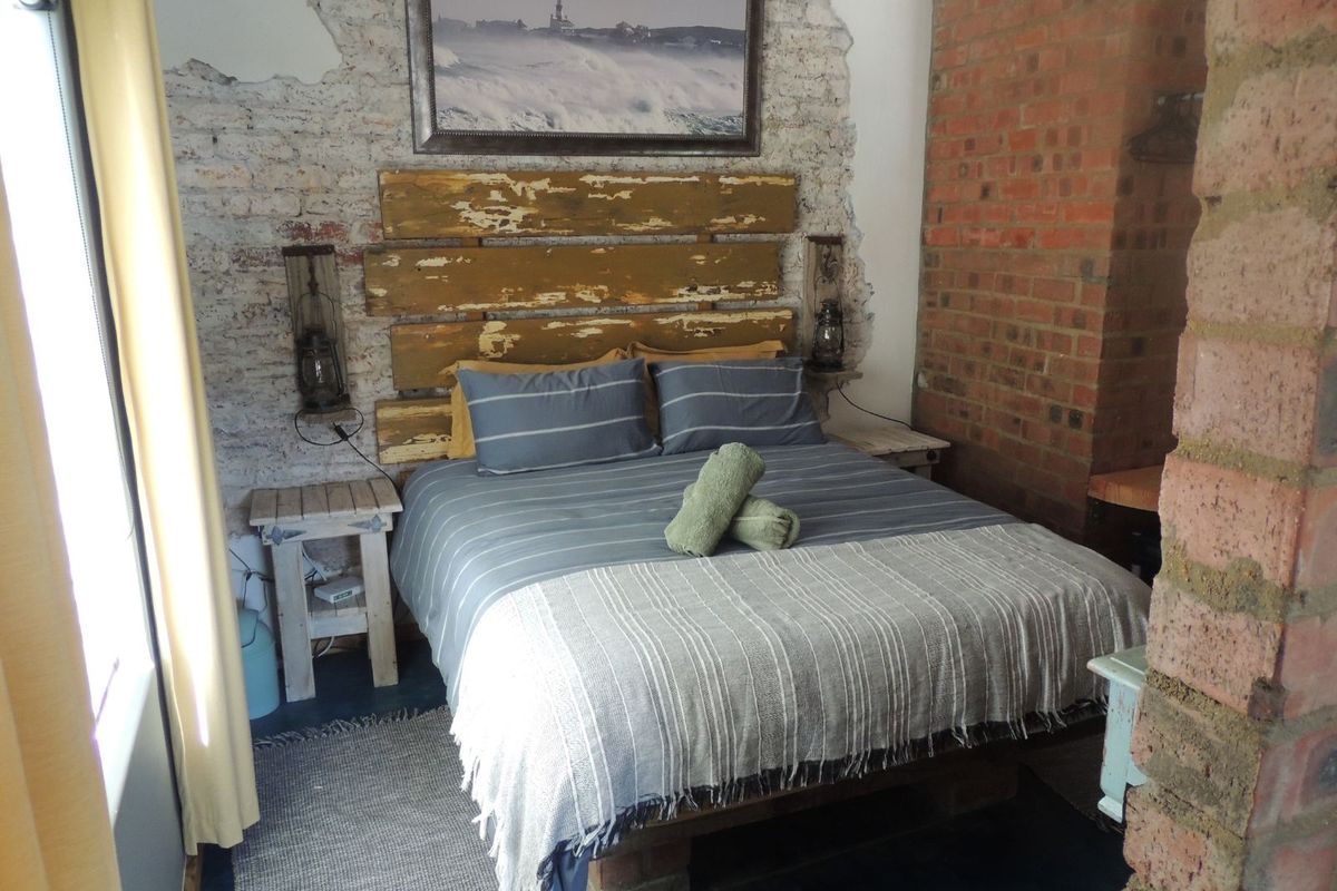 A rustic-style bedroom featuring exposed brick walls, a unique industrial-inspired headboard, and a warm, textured aesthetic.