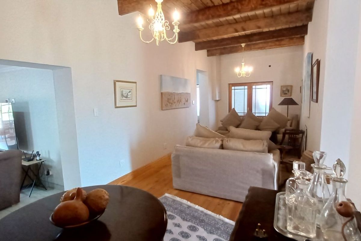 A spacious living area featuring exposed timber ceiling beams, hardwood flooring, and traditional chandelier lighting, creating a warm and inviting atmosphere.