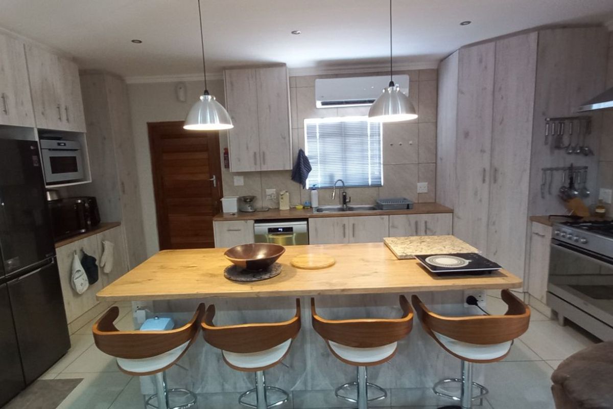 Modern kitchen featuring light wood-grain cabinetry, a central island with breakfast bar seating, stainless steel appliances, and recessed lighting.