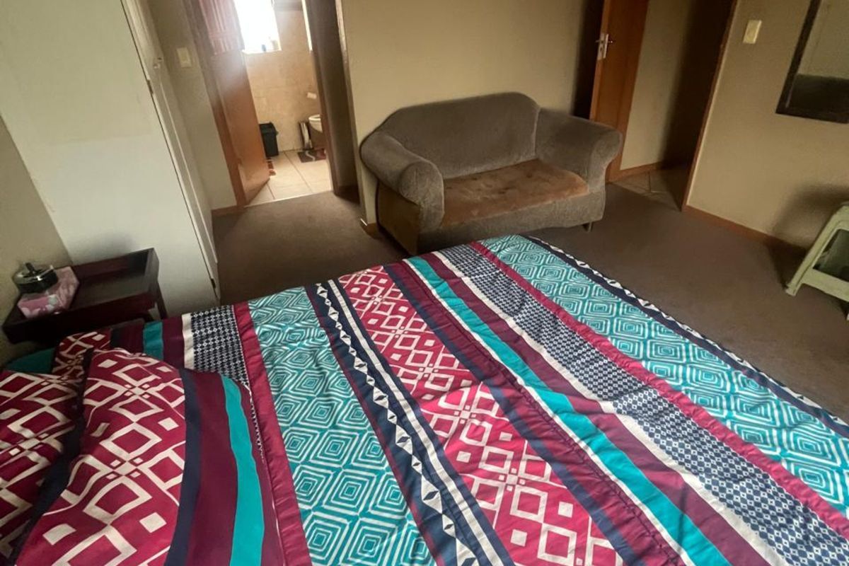 A bedroom featuring carpeted flooring, built-in cupboards, and an en-suite bathroom access point.