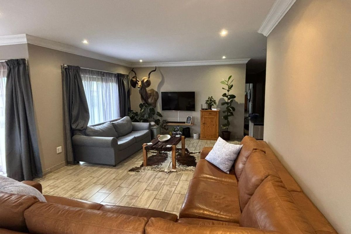 Spacious living room featuring tiled flooring, recessed ceiling lighting, and crown molding, providing a comfortable and well-maintained area for relaxation.