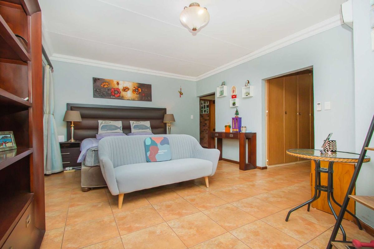 Spacious bedroom featuring tiled flooring, built-in cupboards, and crown molding, offering a comfortable and functional living space.