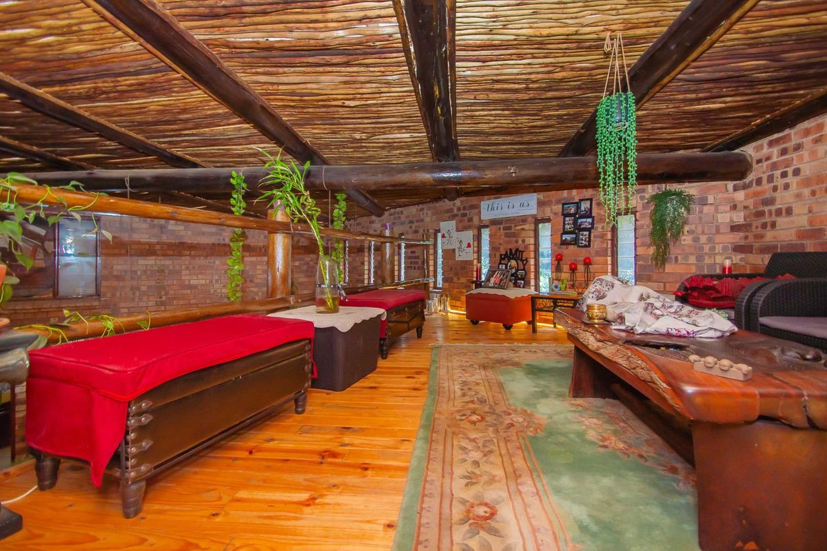 A rustic living area featuring exposed timber beam ceilings, brick walls, and polished wooden flooring, creating a warm and character-filled interior space.