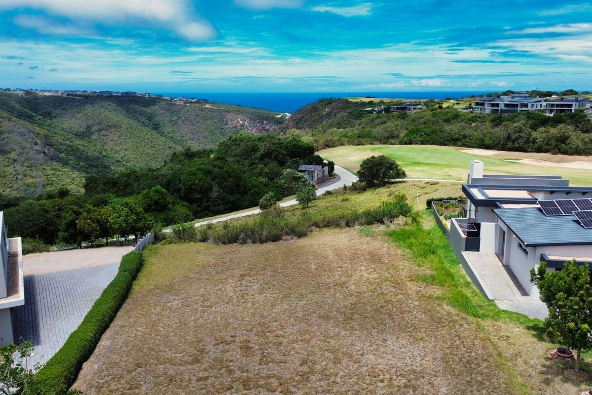 Aerial view of a vacant residential plot situated in a scenic estate, featuring surrounding greenery, coastal views, and adjacent modern residential properties.