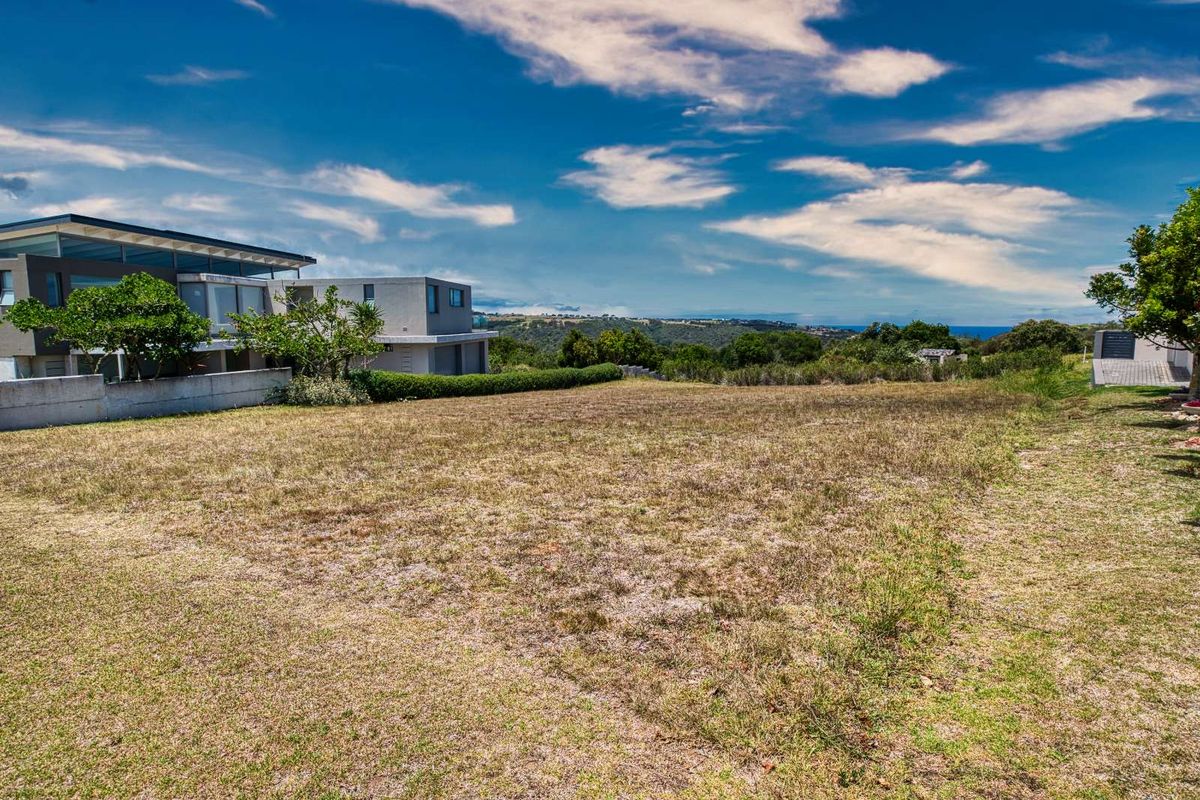 A vacant residential plot featuring established grass, boundary walling, and scenic coastal views, situated in a developed neighborhood.