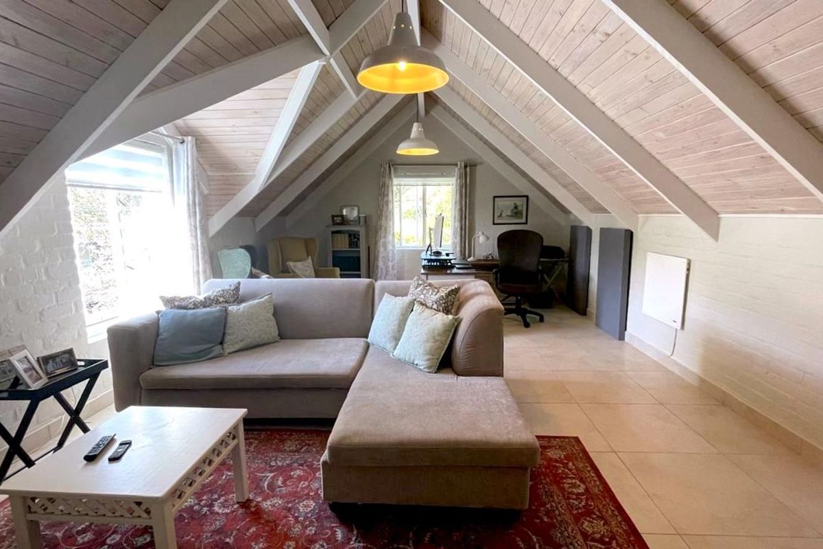 Spacious attic-style living area featuring vaulted timber-clad ceilings, exposed beams, tiled flooring, and integrated office space.