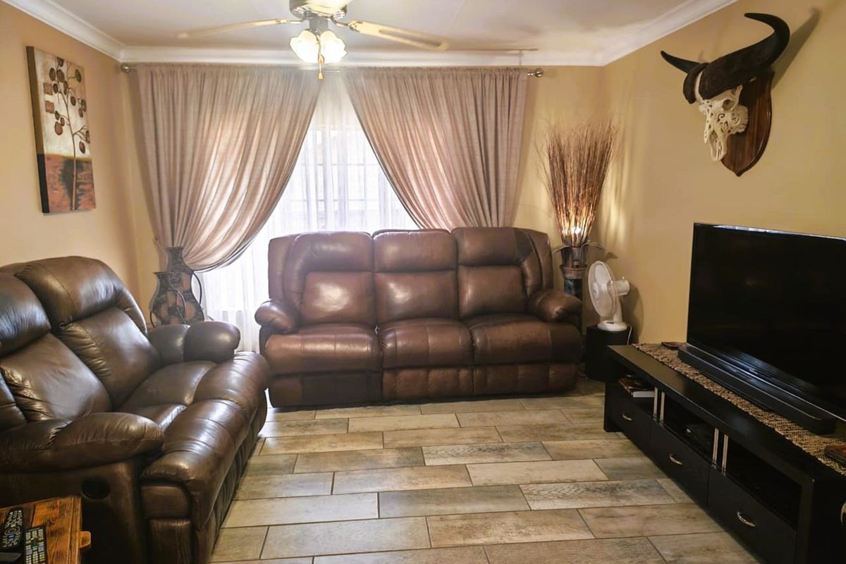 A comfortable living room featuring wood-look tiled flooring, a ceiling fan, and neutral wall tones, providing a functional and inviting space.