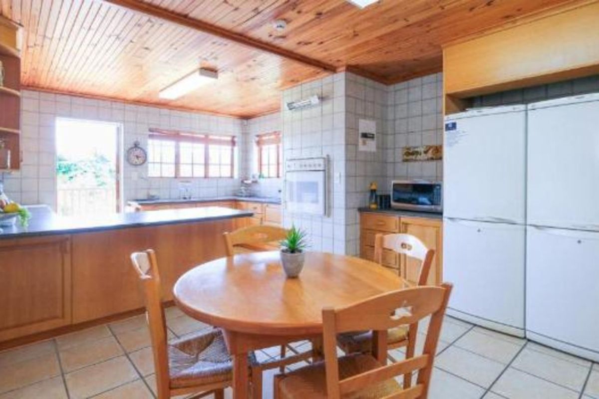 A functional kitchen featuring wooden cabinetry, tiled countertops, and a wood-paneled ceiling, offering a traditional aesthetic with ample storage and workspace.