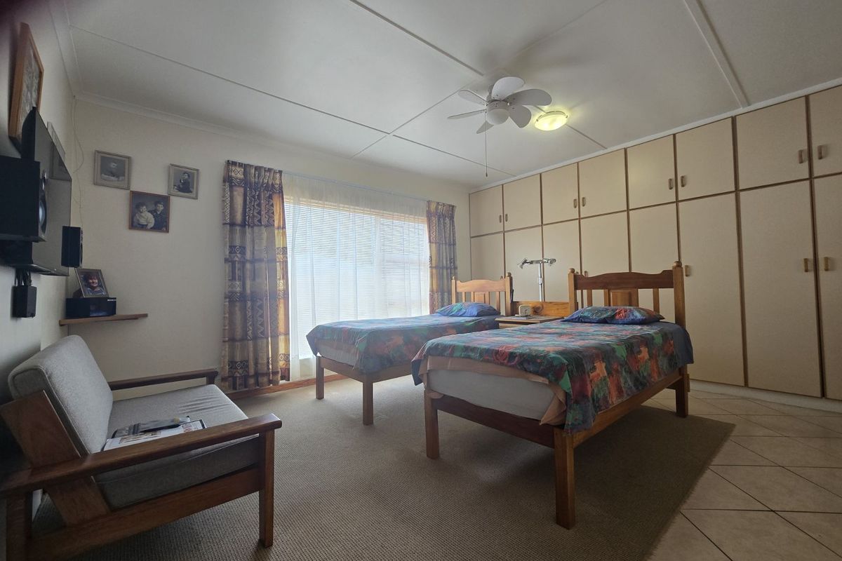 A bedroom featuring built-in floor-to-ceiling cabinetry, a ceiling fan, and tiled flooring.