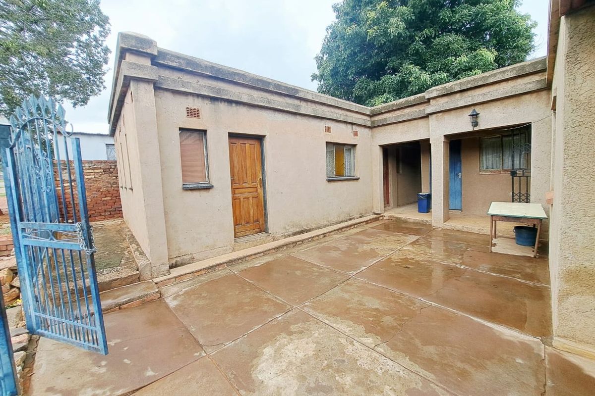 A rear courtyard area featuring concrete paving, exterior masonry walls, and access to the main dwelling structure.