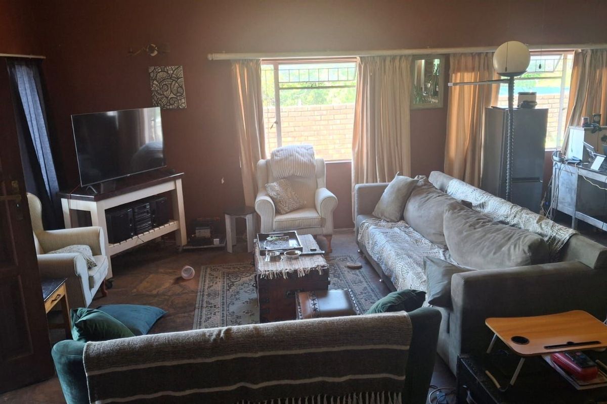 A spacious living room featuring dark wall finishes, tiled flooring, and large windows that provide natural light.