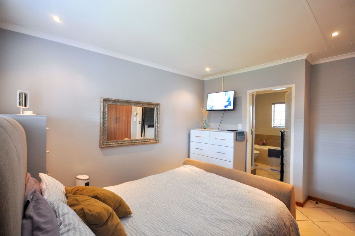 A well-maintained bedroom featuring neutral wall tones, recessed ceiling lighting, and an en-suite bathroom access.