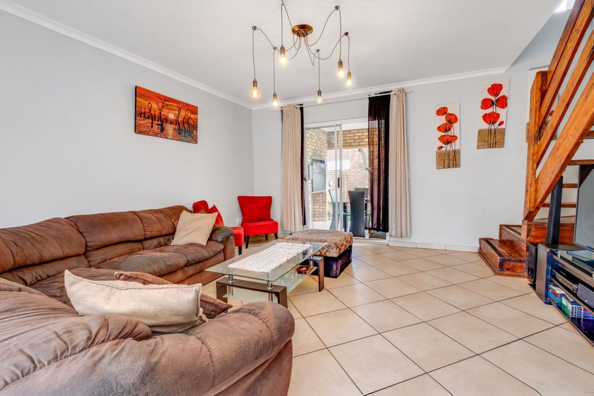 Spacious living room featuring tiled flooring, a wooden staircase, and sliding glass doors providing access to the outdoor patio area.