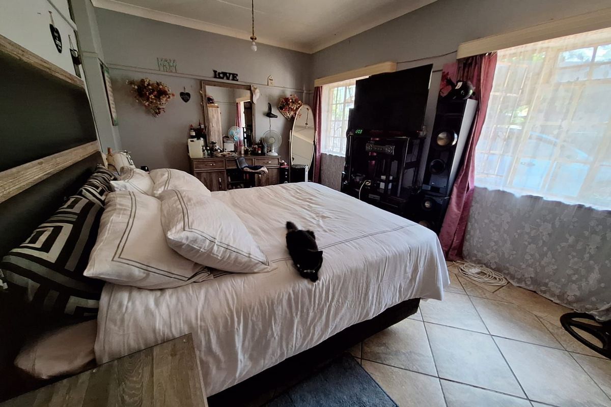 A spacious bedroom featuring tiled flooring, large windows allowing natural light, and neutral wall finishes.