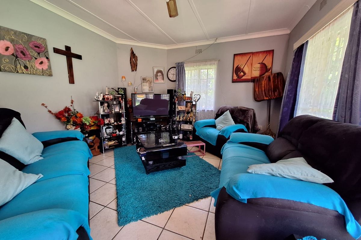 A living room featuring tiled flooring, a ceiling fan, and large windows that provide natural light to the space.