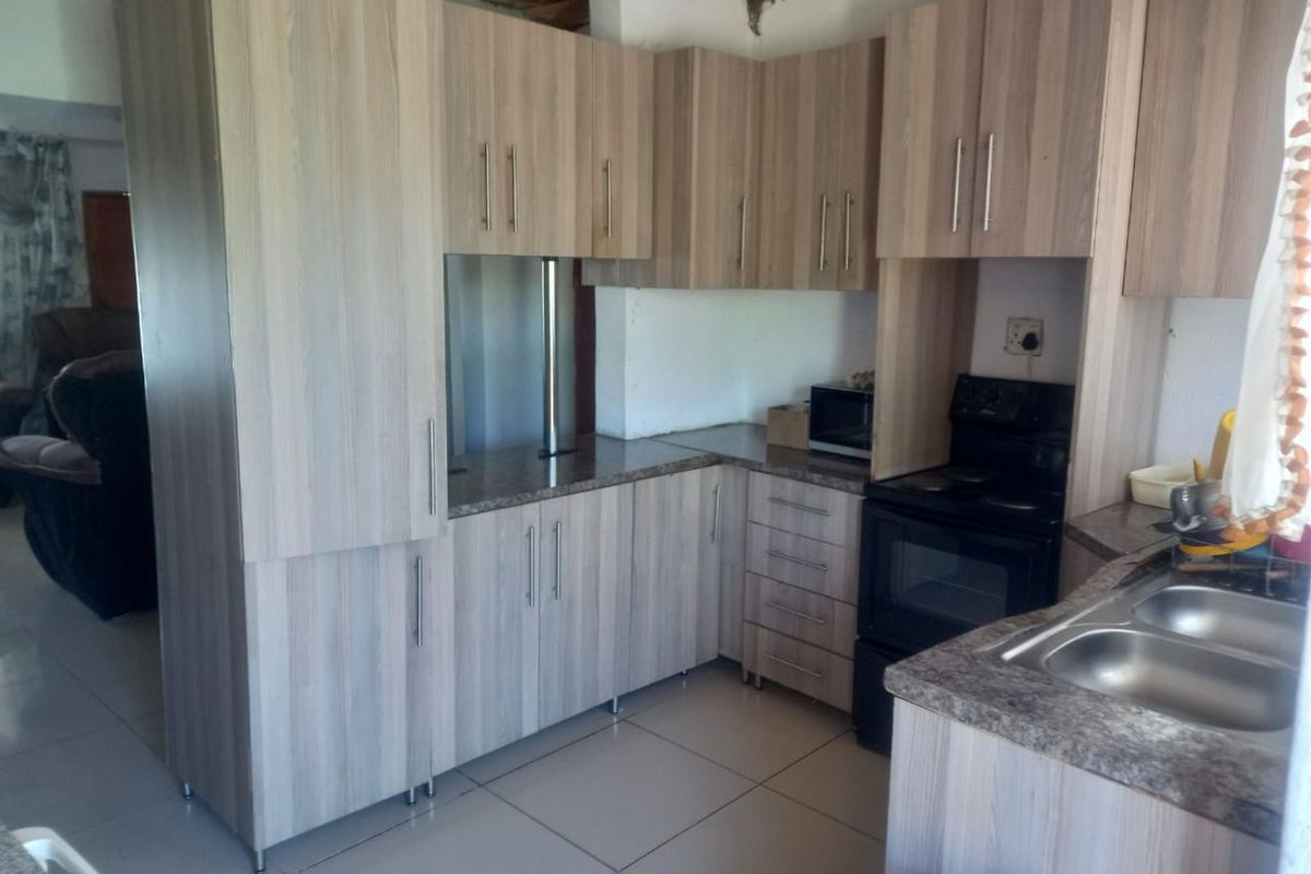 Kitchen featuring light wood-grain cabinetry, laminate countertops, and a double-basin sink, requiring finishing touches to the ceiling and wall areas.