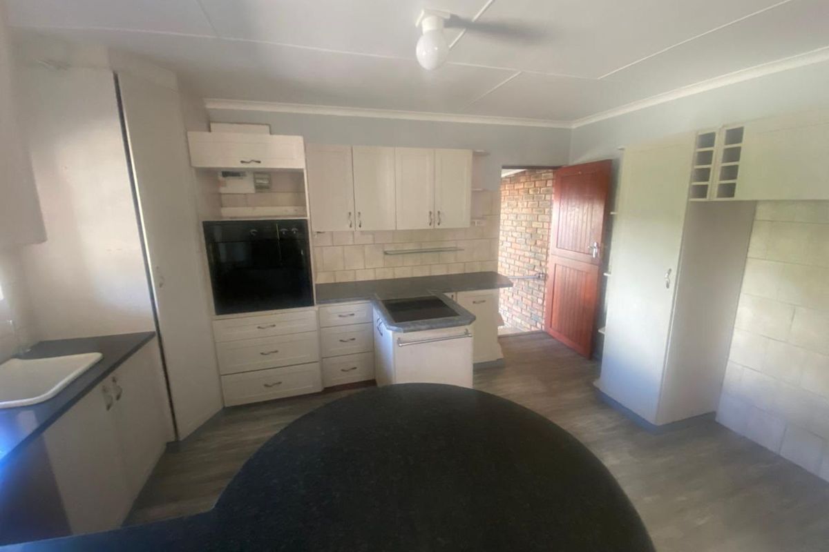 A functional kitchen featuring built-in cabinetry, an integrated oven, a hob, and a breakfast bar, with direct access to an exterior brick doorway.