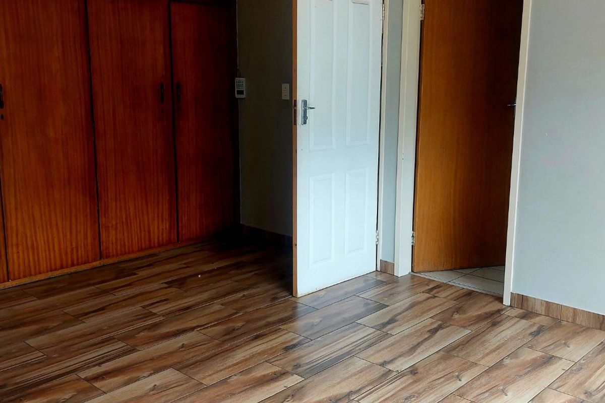 A bedroom featuring wood-look tile flooring and built-in wooden cupboards, providing functional storage space.