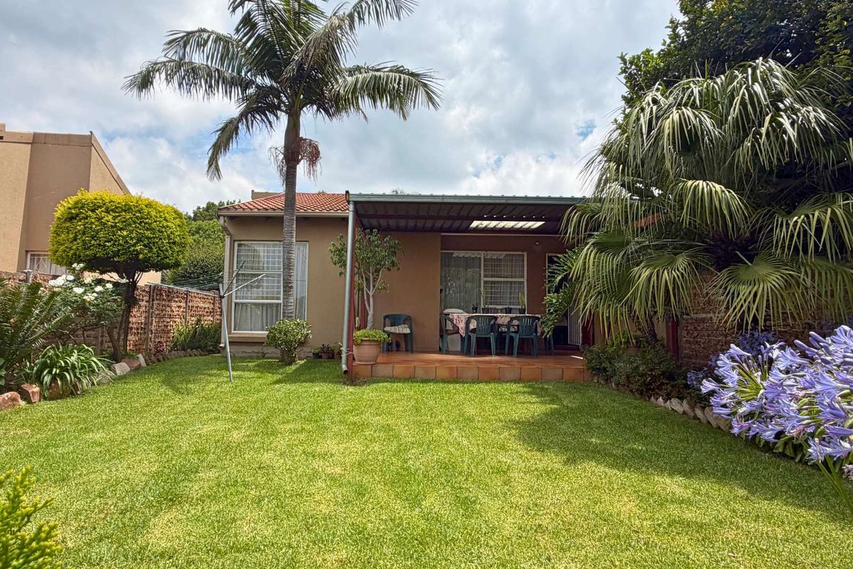 A private rear garden featuring a covered patio area, established landscaping, and a well-maintained lawn, providing a pleasant outdoor living space.